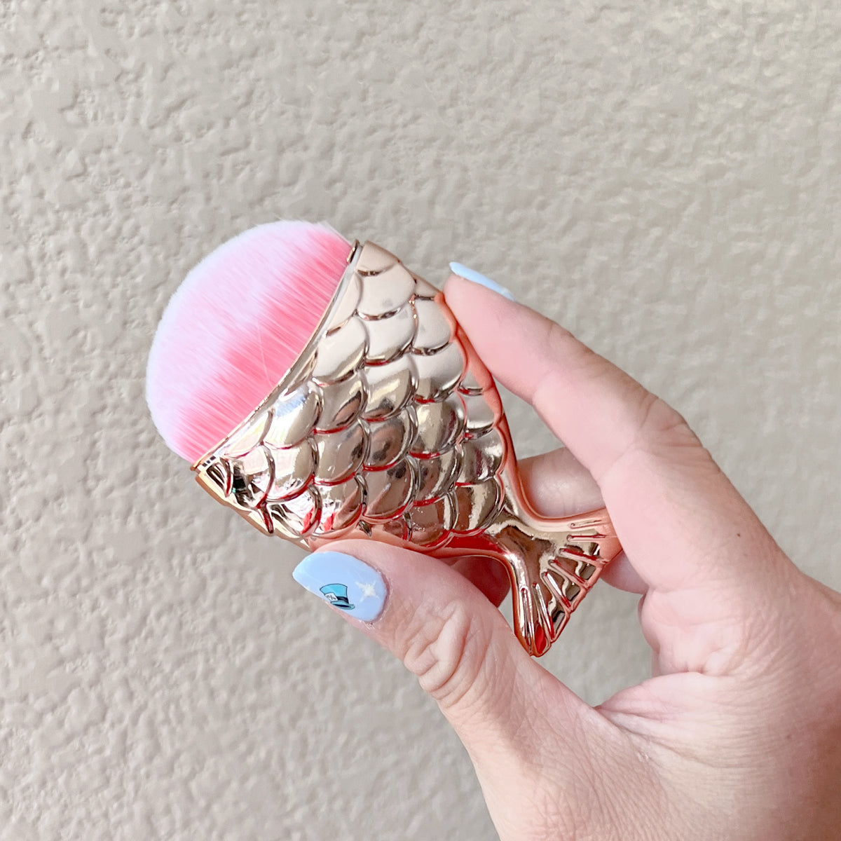 Mermaid tail shaped dusting brush with soft synthetic bristles, approximately 3 inches long